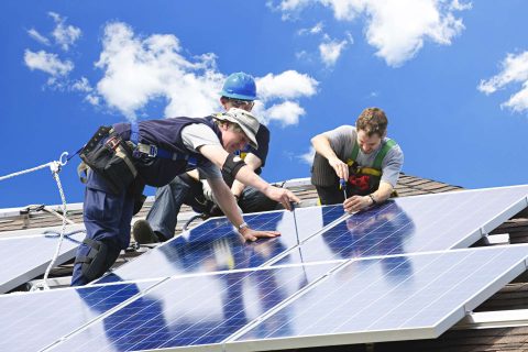Contractors installing solar panels on a roof image